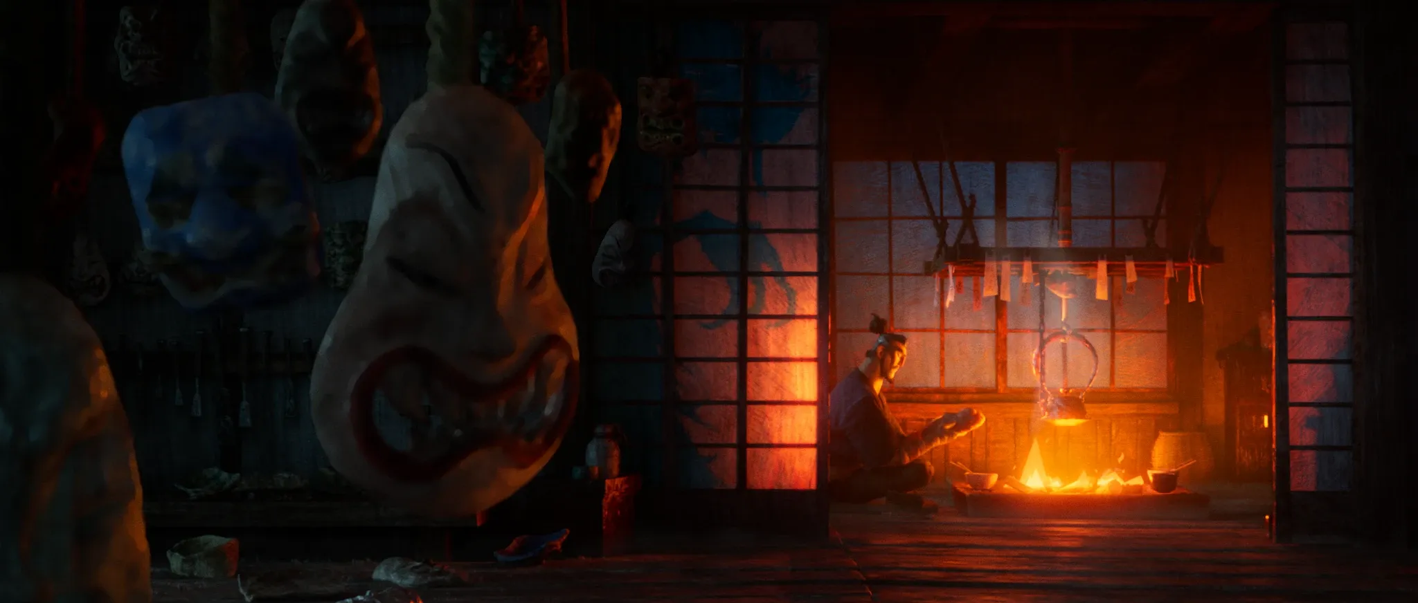 Tengu no Uta — the mask workshop: finished masks hanging in the foreground, Hisashi small by the fire